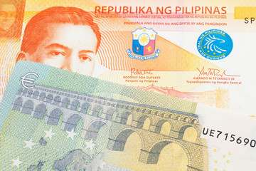 An orange twenty piso note from the Philippines close up in macro with a five Euro note from the European Union eurozone