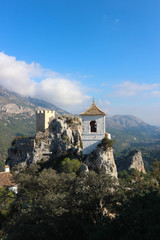Fototapeta na wymiar View to castle watch tower and bell tower in Castell de guadalest with mountains on the background, Spain