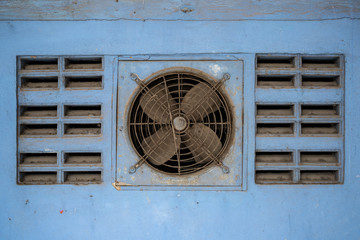 Dusty ventilation fan on blue wall