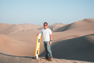 Man enjoying sand boarding at Huachina desert sand dunes Peru South America