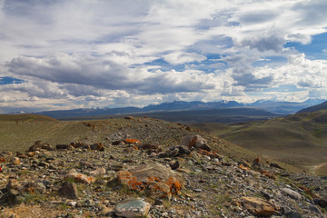 Panoramic view of a mountain valley summer, soft light, white clouds, blue sky. Altai mountains. Big rocks in front view.