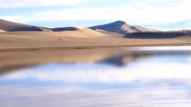 A large lake on the edge of a sandy desert. Mongolia sandy dune desert Mongol Els near lake Durgen Nuur. Khovd province, Western Mongolia.