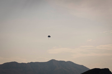 Skydiver flying far in the sky over the mountains.