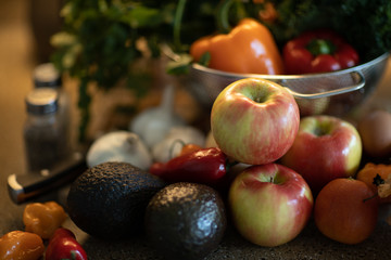 vegetables on a kitchen counter with salt and pepper shaker with close up on an apple