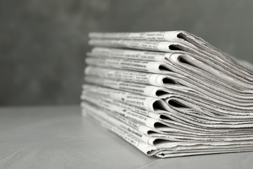 Stack of newspapers on light grey stone table, closeup. Journalist's work