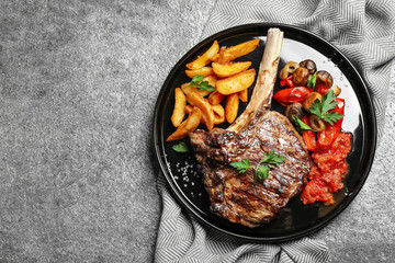 Delicious grilled ribeye served on grey table, flat lay. Space for text