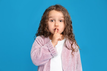 Portrait of cute little girl on light blue background
