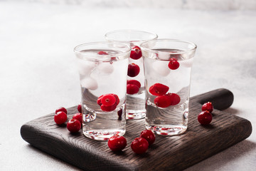 Stacks of vodka and cranberries on a wooden stand and background. Copy of the space. Bar alcoholic beverage tincture.