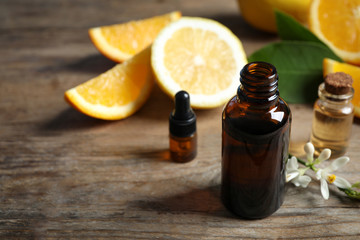 Bottles of citrus essential oil on wooden table. Space for text