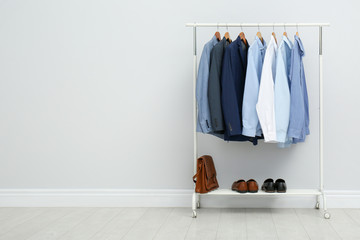 Rack with stylish men's clothes in room. Space for text
