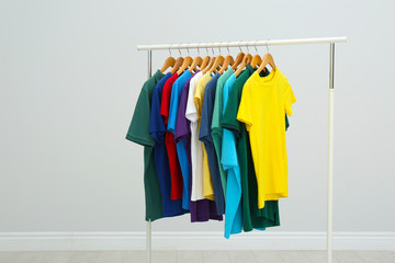 Rack with stylish colorful t-shirts in room