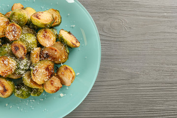 Delicious roasted brussels sprouts with grated cheese on grey wooden table, top view. Space for text