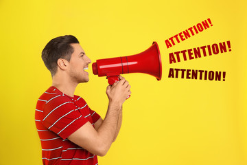Handsome man with megaphone on yellow background