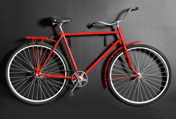 Red bicycle hanging on black wall indoors