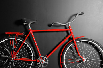 Fototapeta na wymiar Red bicycle hanging on black wall, closeup