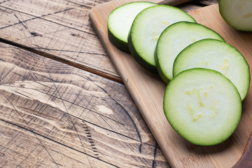 Fresh green zucchini cut into slices on a cutting Board. Wooden rustic table background. Copy space
