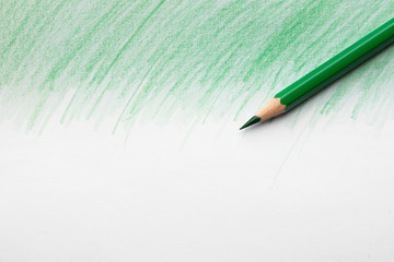 Green pencil on sheet of paper with drawing, top view. Space for text