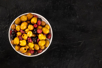 Olives variety. Black, green and red olives, shot from above on a black background with a place for text
