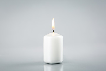 Burning white candle on light grey background