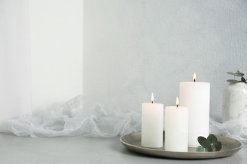 Burning candles on light grey stone table. Space for text