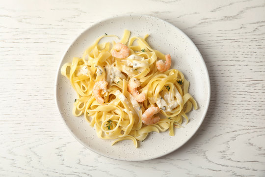 Delicious pasta with shrimps on white wooden table, top view