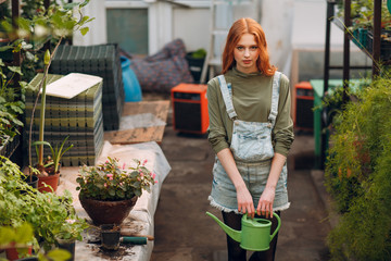 Fototapeta na wymiar Home gardening concept. Young pretty woman with watering can. Spring garden.