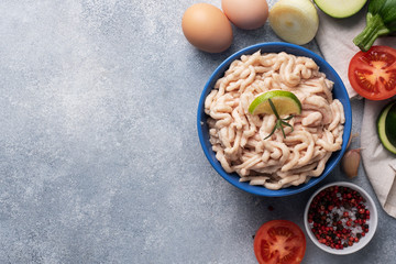 Raw minced chicken on a plate with spices on a gray background and raw vegetables zucchini tomato onion and eggs. Products to prepare the cutlets at home. Copy space