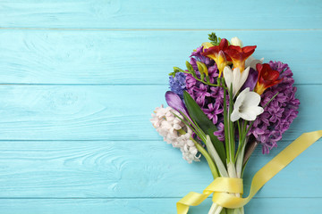 Bouquet of beautiful spring flowers on blue wooden table, top view. Space for text
