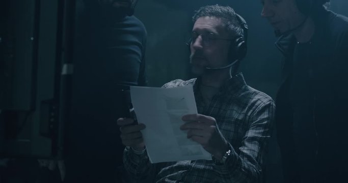 Director holding the script and discussing with technicians