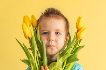 Cute little boy holding a bouquet of flowers. Tulips. Mothers Day. International Women's Day. Portrait of a happy little boy on a white background. Spring.