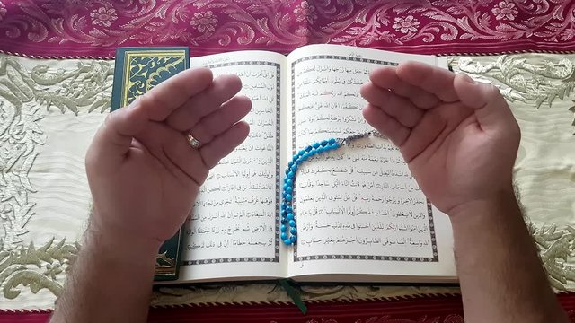 Islamic praying - Prayer hands reading the Koran and rosary in hand