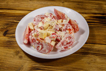 Tasty salad with crab sticks, cheese, tomato and mayonnaise on wooden table