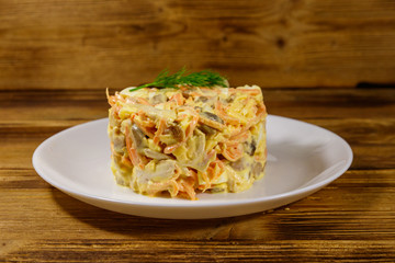 Tasty salad with chicken breast, roasted mushrooms, carrots, grated cheese, eggs and mayonnaise on wooden table