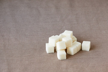 Fototapeta na wymiar Heap of lump sugar on a brown textile background