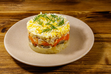 Tasty layered salad with potatoes, chicken breast, marinated mushrooms, carrots, eggs and mayonnaise on wooden table