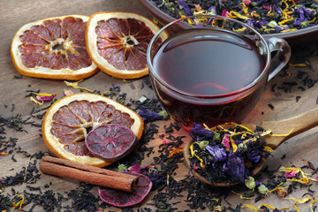 cup of fresh tea and different varieties of tea leaves on a wooden table. blended tea with flower...