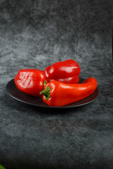Red fresh bell peppers in a ceramic plate.
