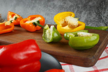 Mixed color bell peppers on a wooden board.