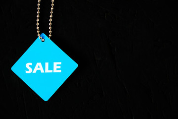 Blue tag with the words sale on a black background.