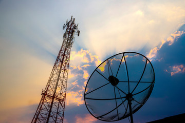 Communications satellite dish and a telecommunications tower at the sunset