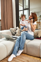 Inventive modern mother with children multitasking in the morning. Mom and baby are modern technologies and gadgets. work at home in the divert.