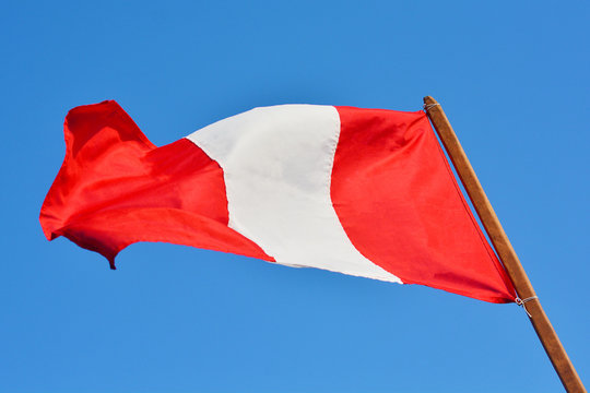 Peruvian flag. Bright blue sky background.