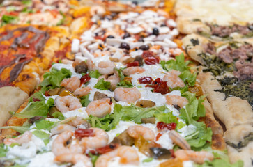 Large assortment of pizza with cheese, seafood, and salmon at an Bergamo pizza store. Italy