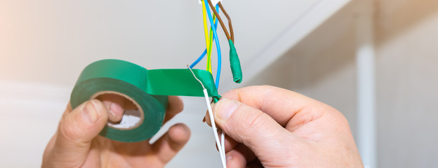 Man is holding adhesive tape in his hands.  Electrical insulator for light bulb. Maintenance repair...