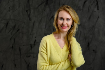 Photo of happy pretty blonde caucasian woman in yellow sweater on gray background