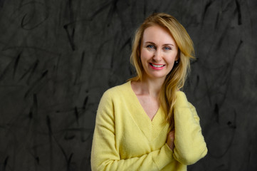 Fototapeta premium Photo of happy pretty blonde caucasian woman in yellow sweater on gray background