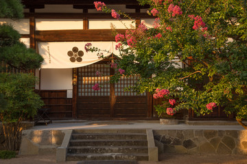 Photograph of the door of a Japanese temple with a tree branch in the foreground