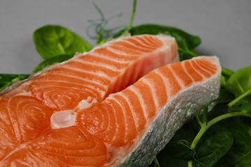 Salmon steak raw fish on spinach leaf and microgreens,  prepared for cooking. top view. grey background