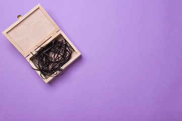 open wood box with black filler lying on purple background, top view with copy space