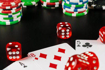 Dice and chips on black table close up